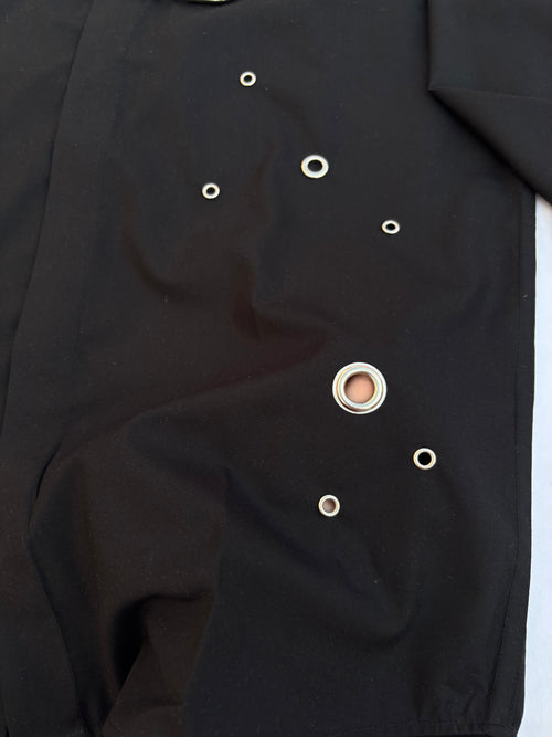 Close-up of a black garment with button details on a white background