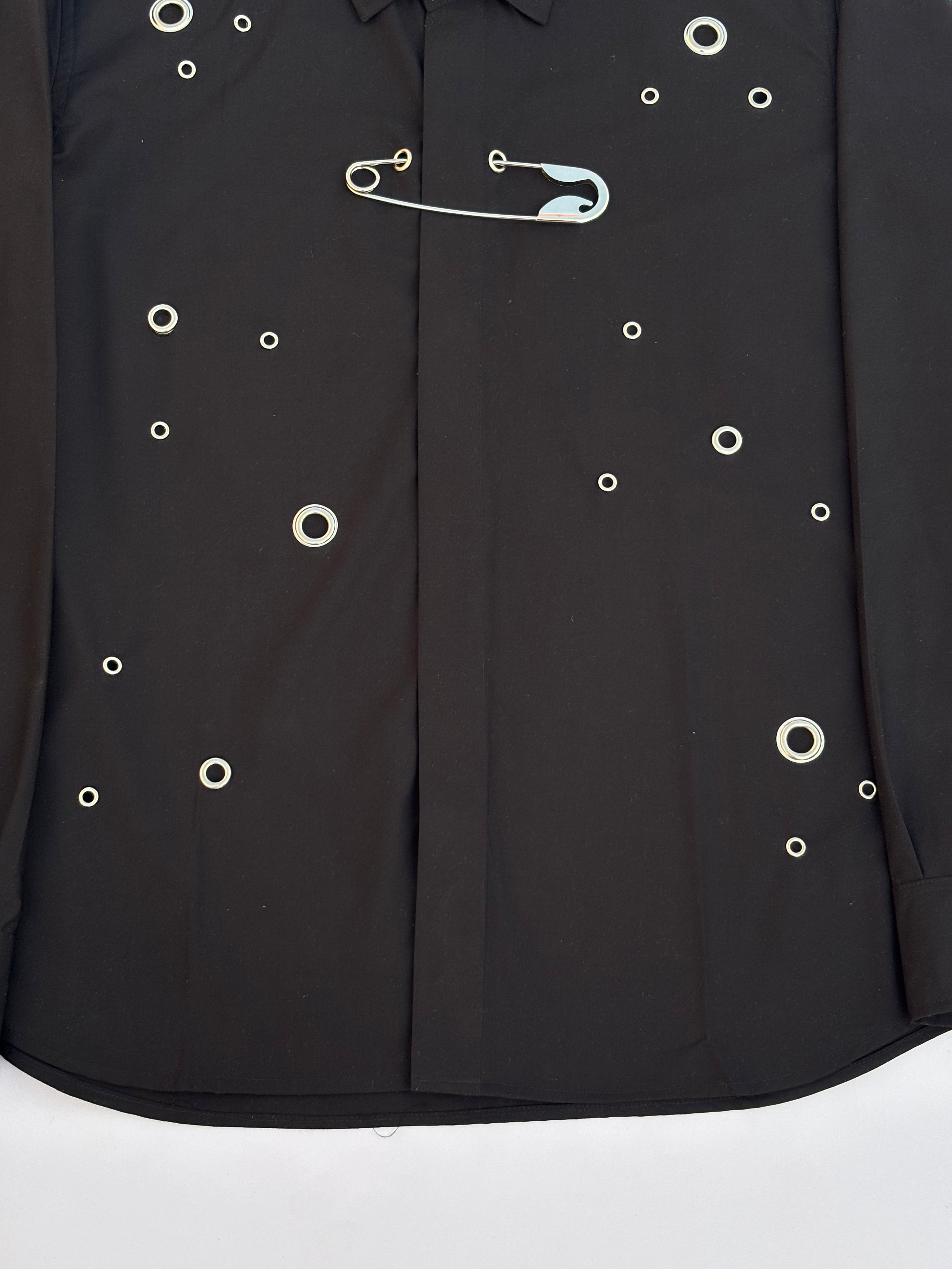 Black shirt with white buttons and a safety pin on a white background