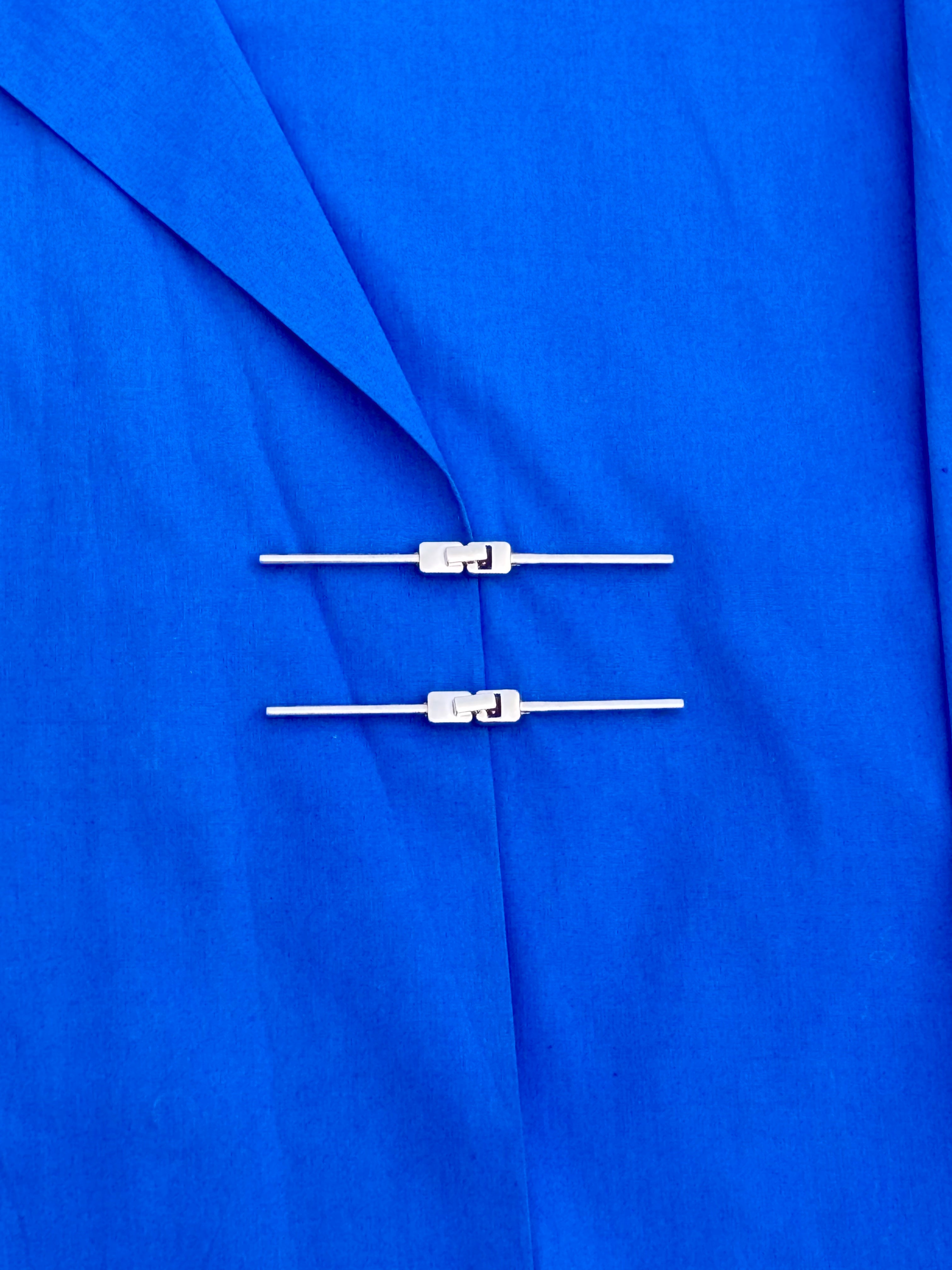 Two silver buttons on a blue fabric background