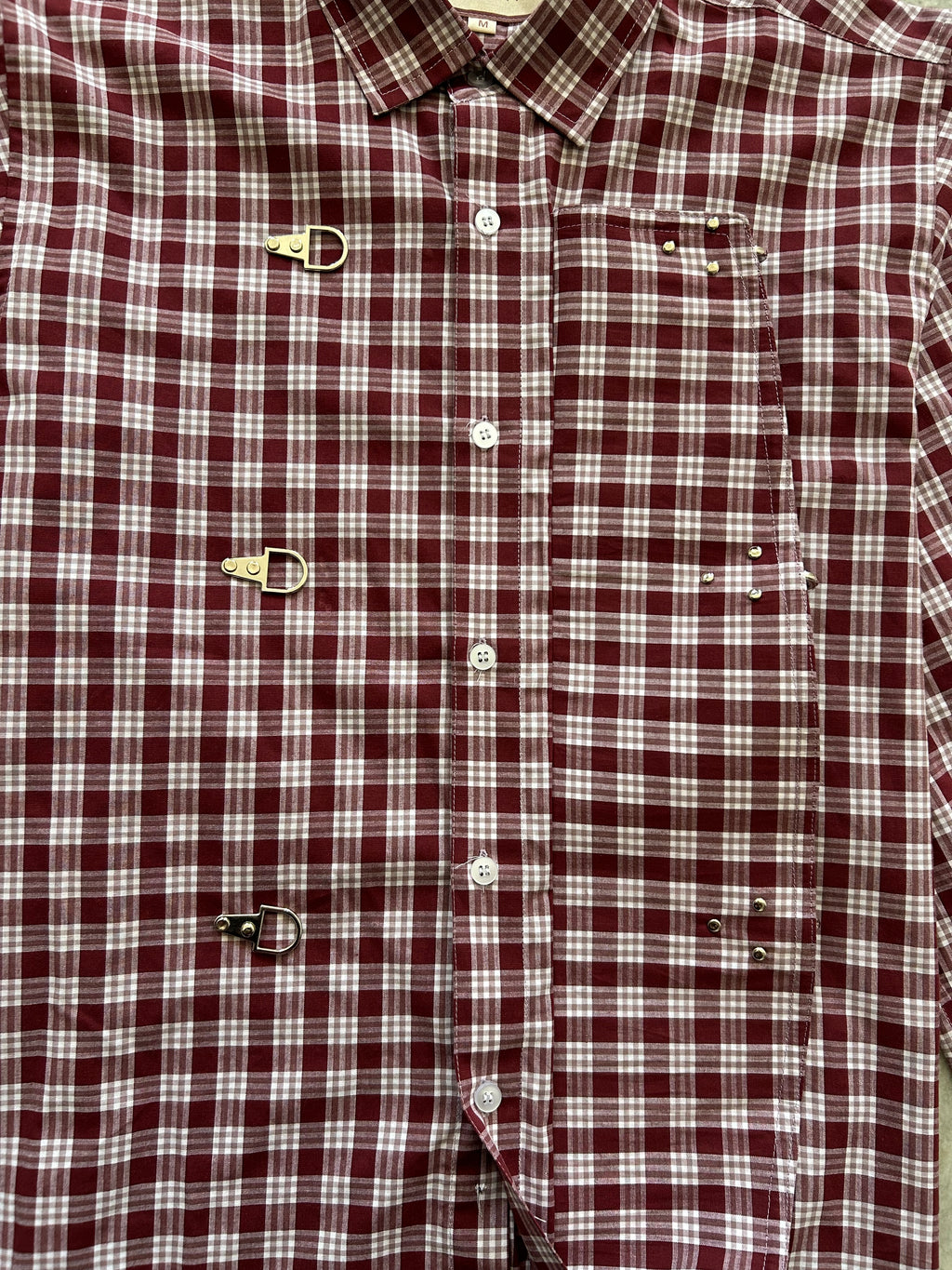 Close-up of a maroon and white checkered shirt with buttons and suspenders.