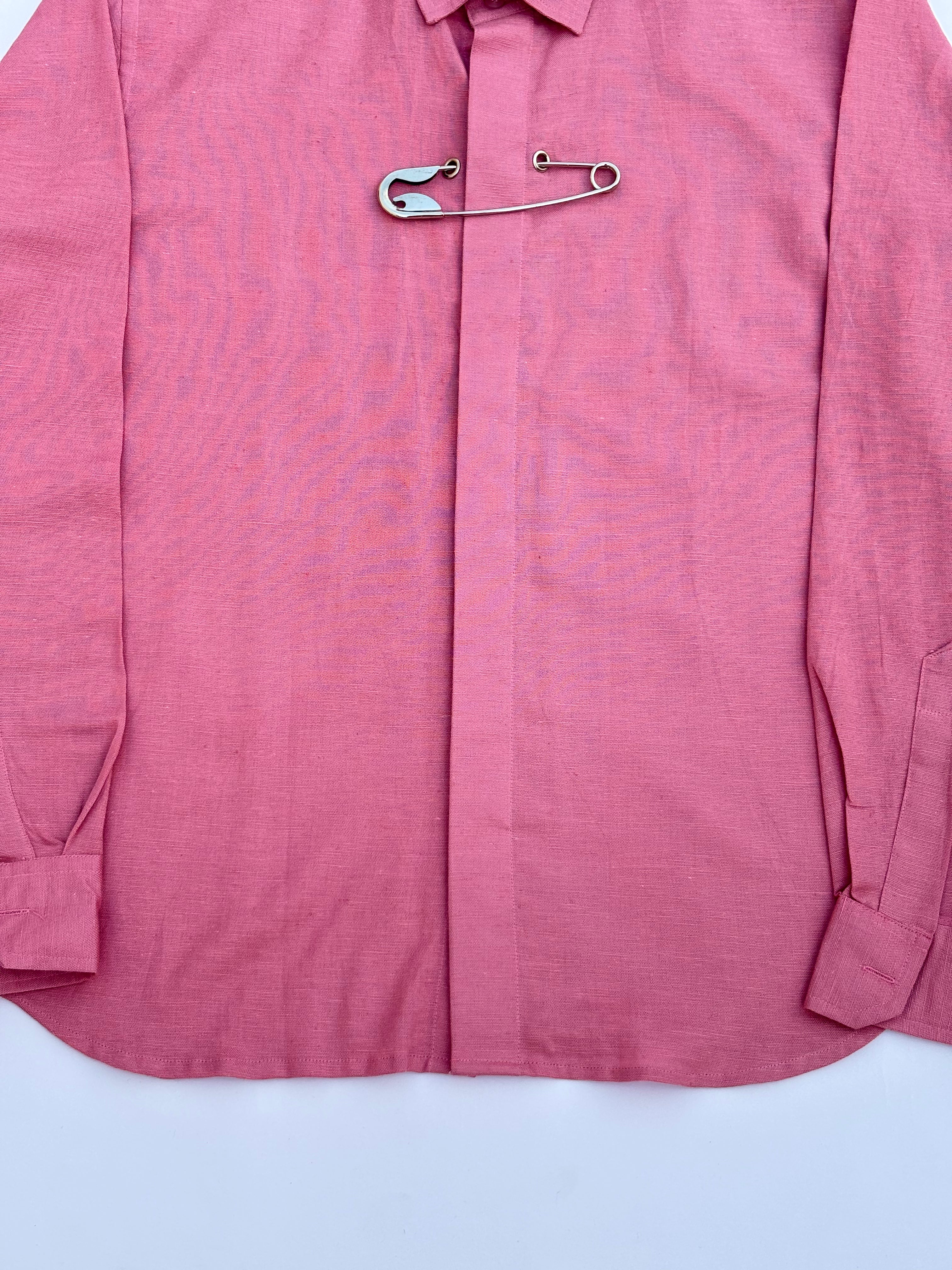 Pink shirt with a safety pin on a white background