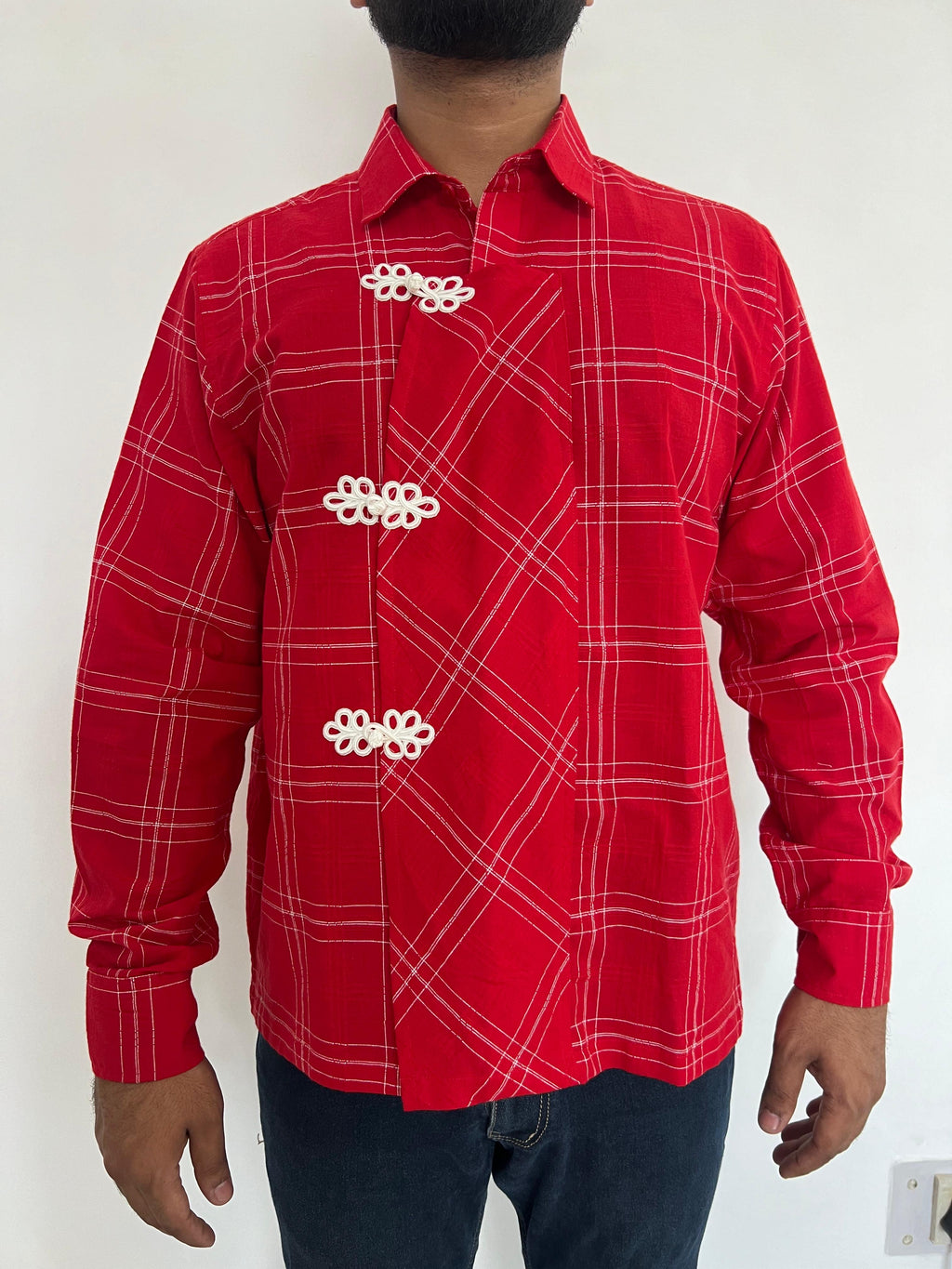 Red checkered shirt with white patterns worn by a person on a white background