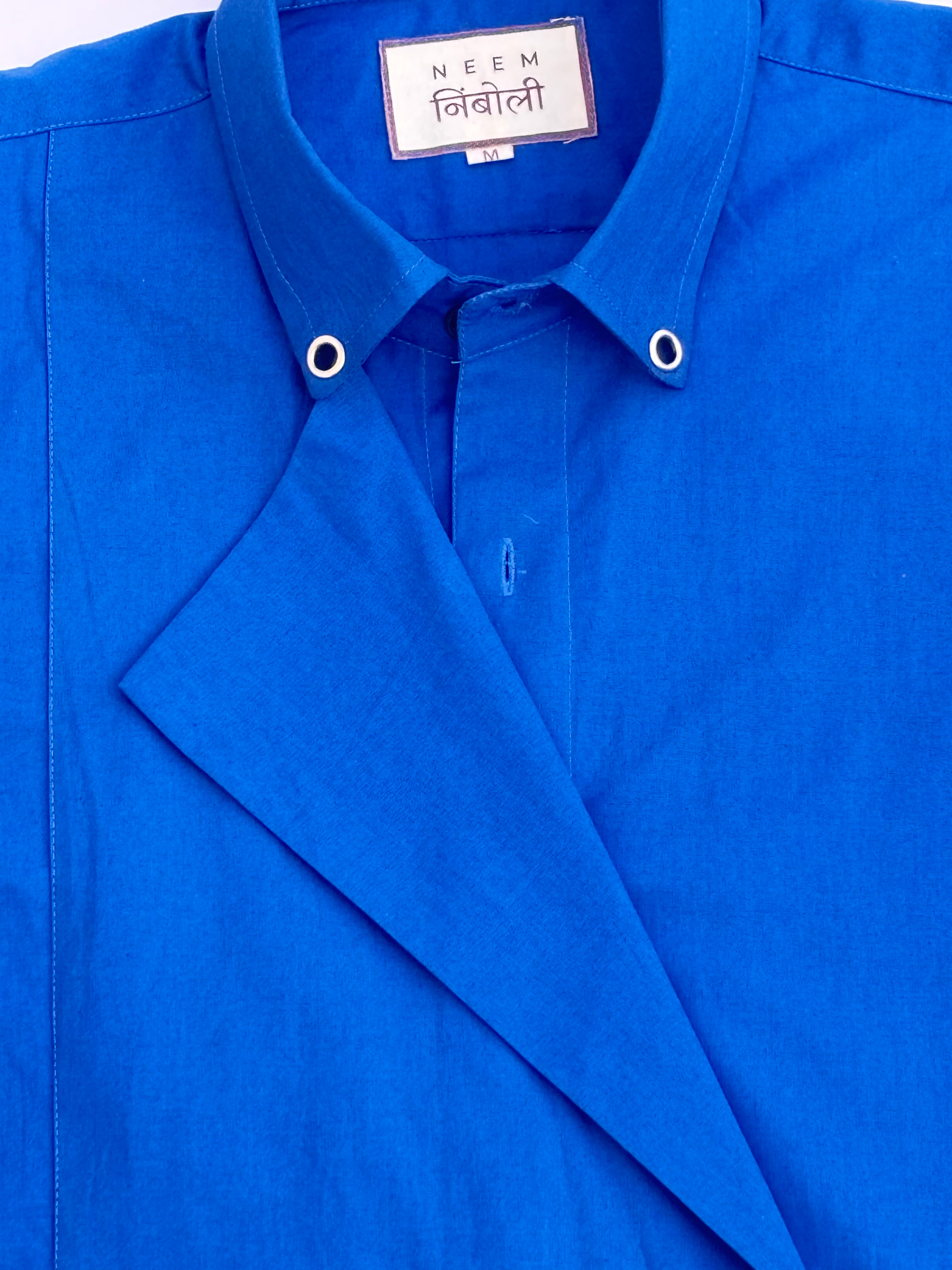 Blue shirt with a visible brand label on a white background