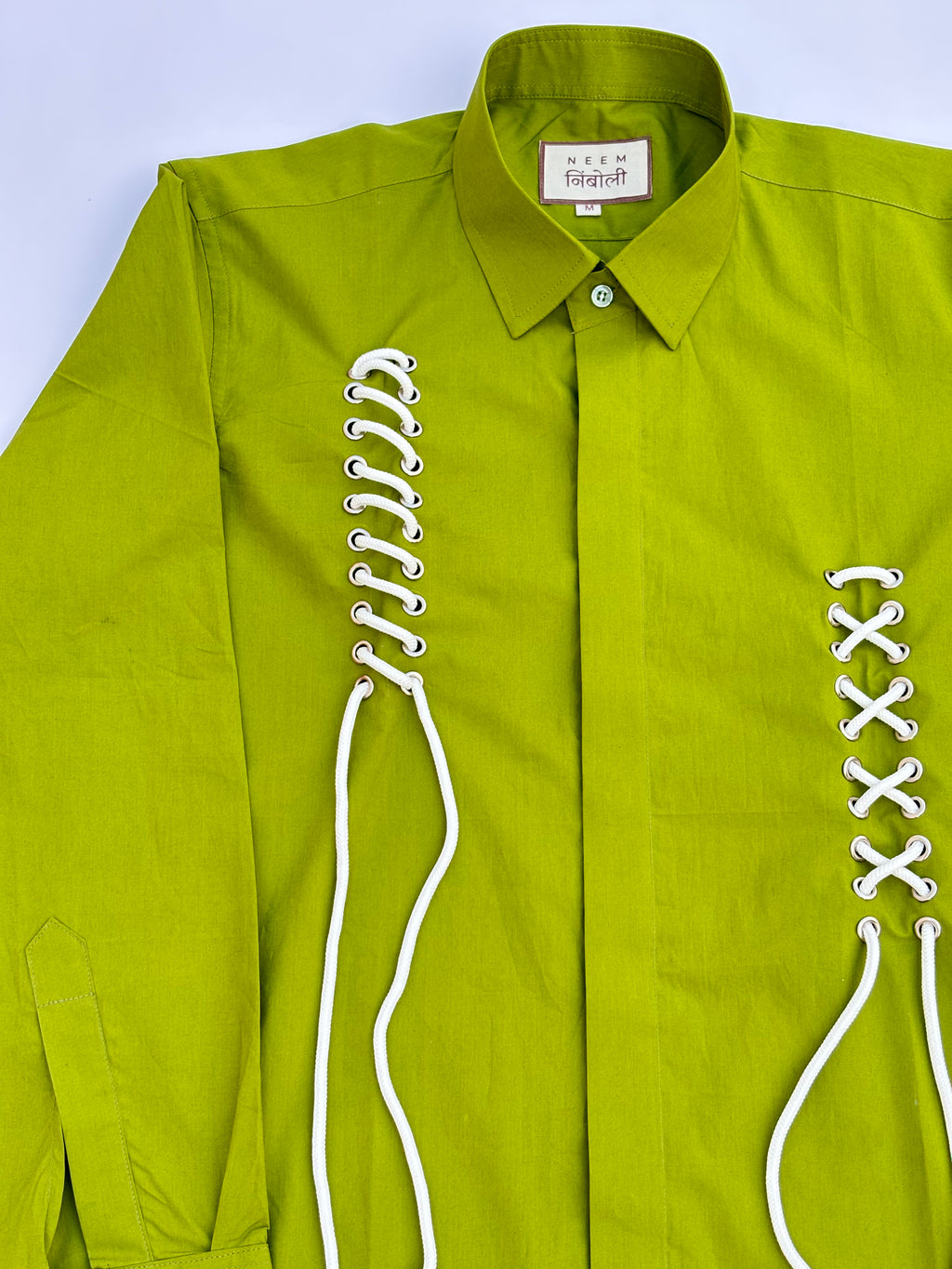 Green shirt with white lace details on a light blue background
